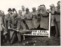 Start of work on Avon Dam, showing officials standing near top water level marker and the first clod