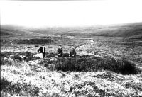 Three men sitting in hut circle on Erme Plains