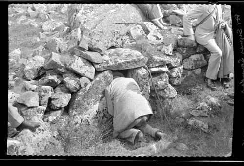 Dr. E. G. Symes Saunders lights his pipe in a kistvaen