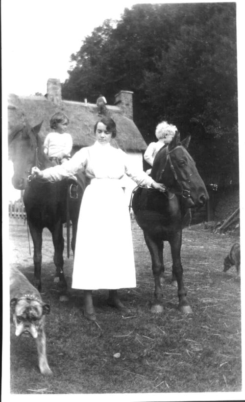 Young woman leading two children on ponies